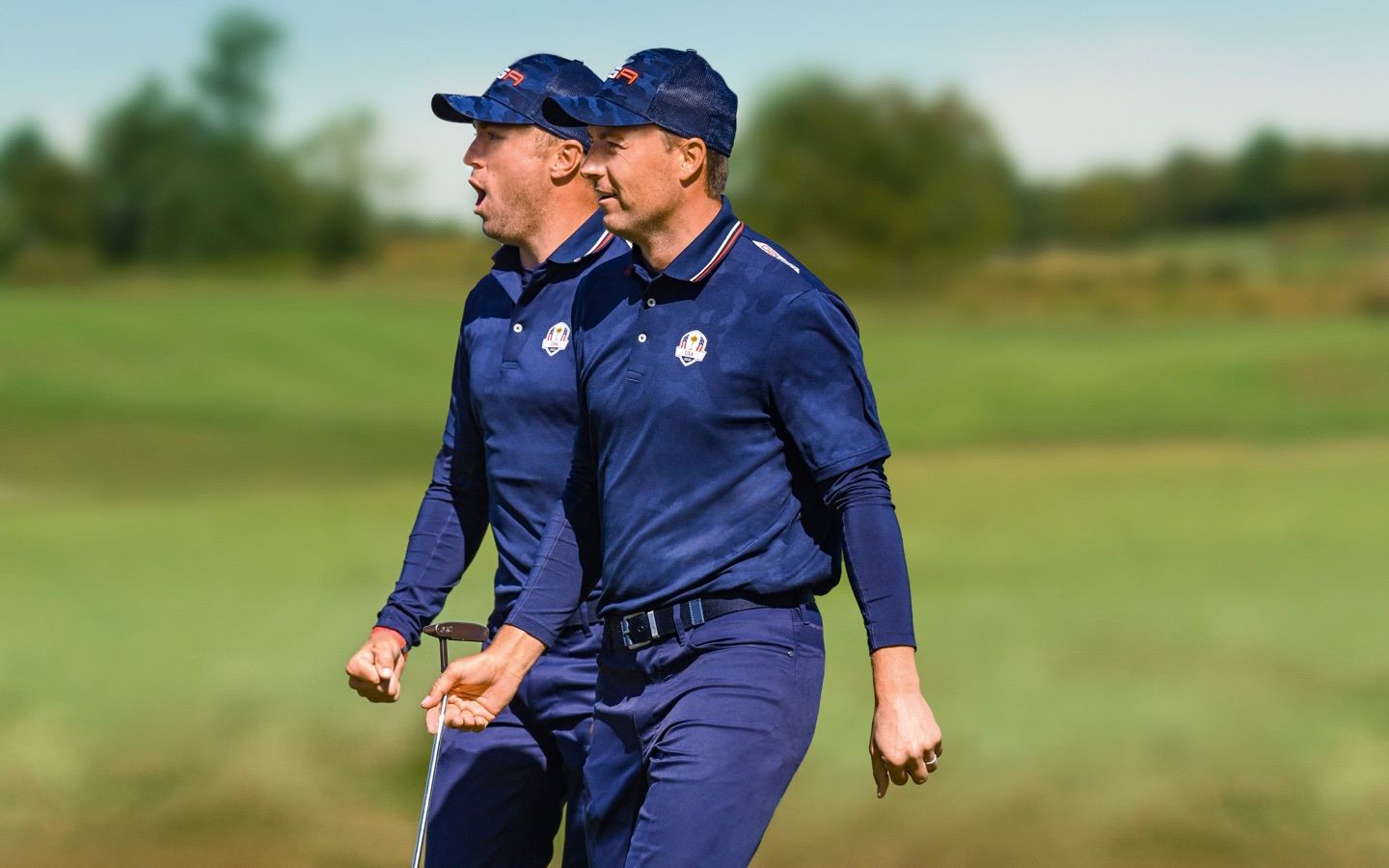 Golfers wearing blue walk the course during the Ryder Cup.