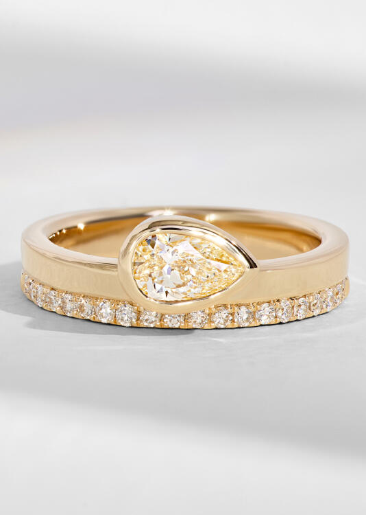 Bridal set with a diamond band and pear shaped diamond engagement ring in yellow gold.