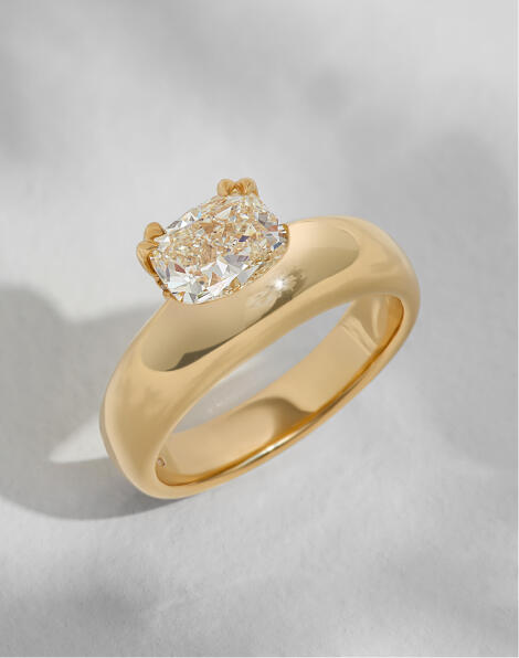An asymmetrical solitaire diamond engagement ring in yellow gold.