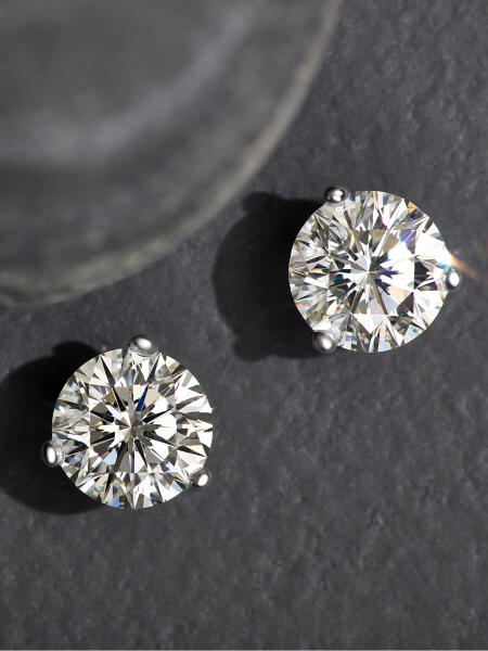 A pair of diamond studs on a grey textured background.