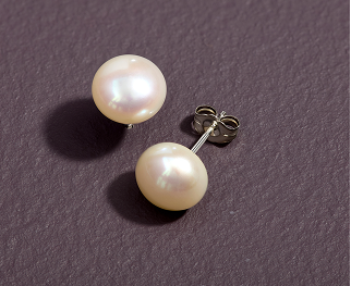 A pair of cultured pearl button stud earrings against a textured purple backdrop