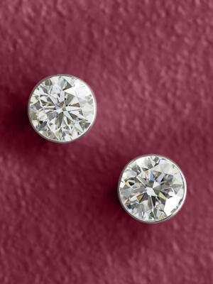 Solitaire diamond studs on a textured purple background