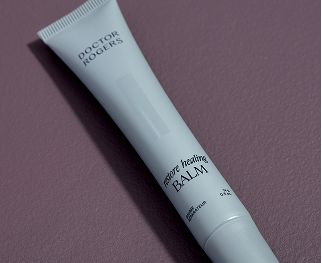 A tube of Doctor Rogers Healing Balm is shown against a textured purple background.