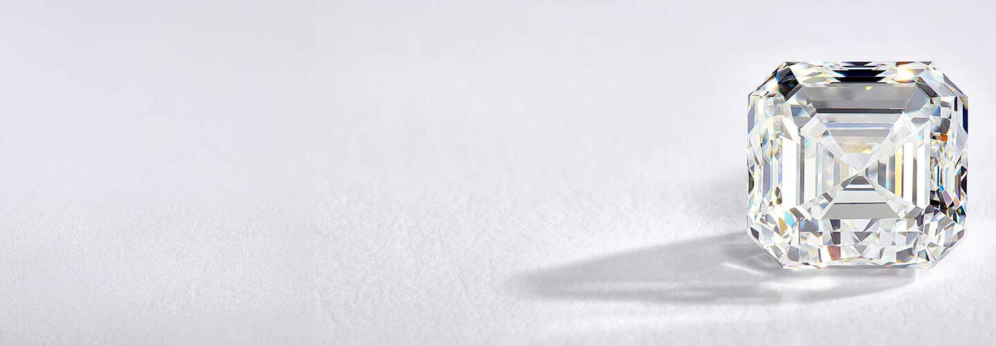 A loosediamond casts a shadow against a backdrop that features a light gray gradient. 