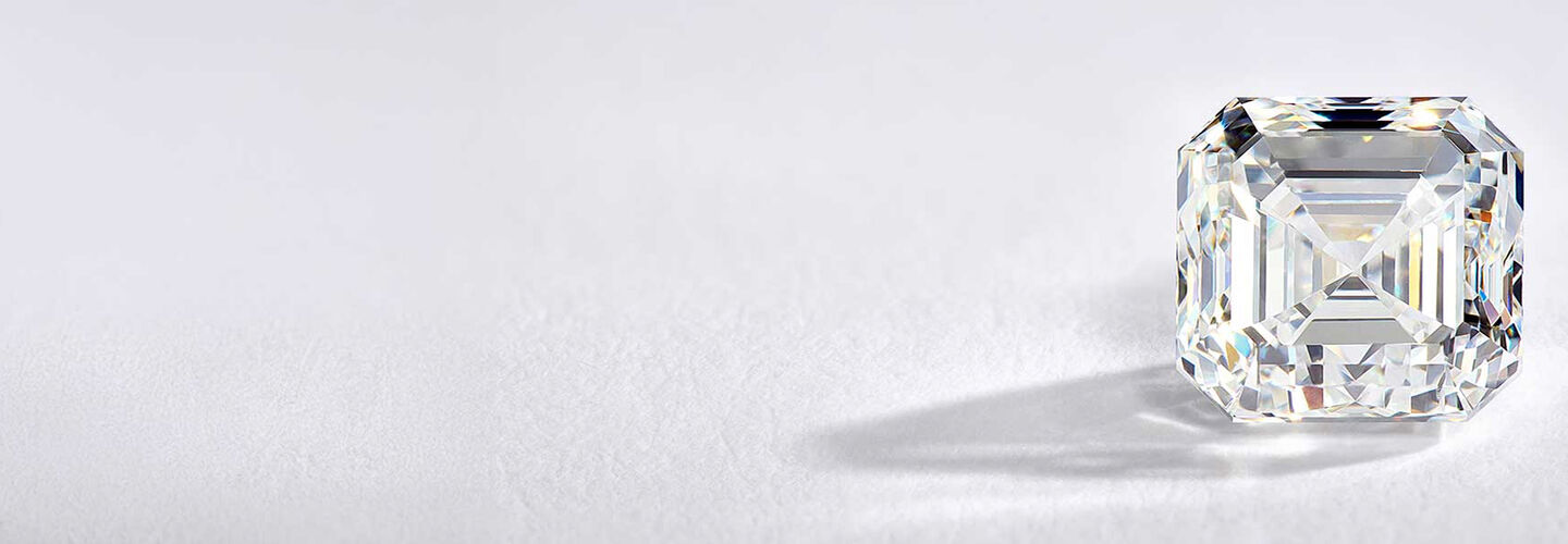 A loosediamond casts a shadow against a backdrop that features a light gray gradient. 