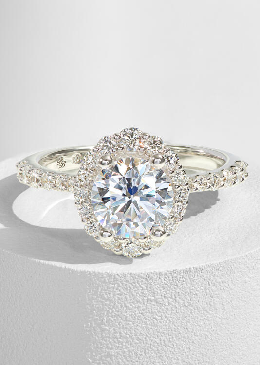 An oval diamond engagement ring with a halo of round diamonds in white gold.
