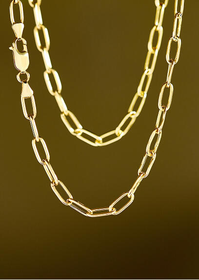 Two strands of a yellow gold link necklace catch the light with a gradient backdrop. 