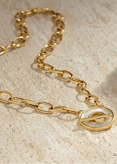 A gold and mother-of-pearl necklace lies on a stone surface.