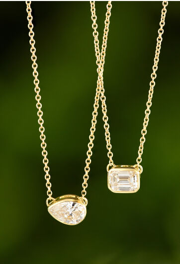 Fancy shaped solitaire diamond necklaces in 14k yellow gold with a green background. 