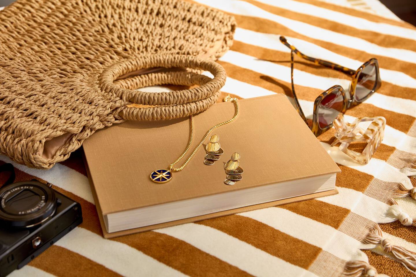 jewelry and a book laying on a striped beach towel