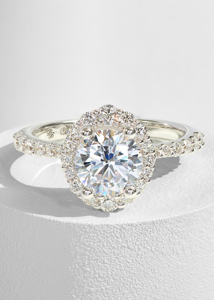 An oval shaped diamond engagement ring with a halo of round diamonds in white gold. 