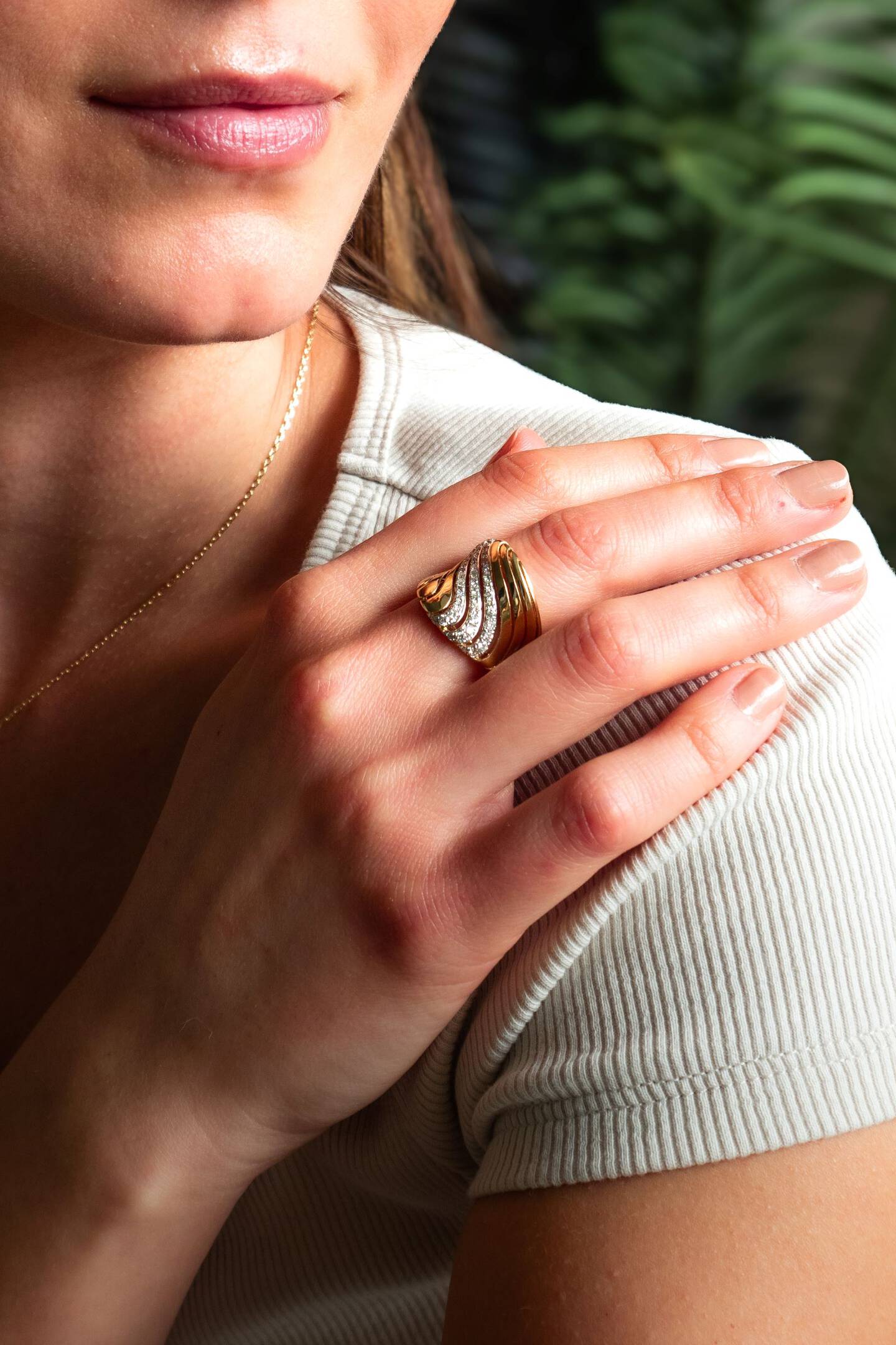 Yellow gold and diamond ring on the finger of a woman. The hand is resting on her shoulder. 