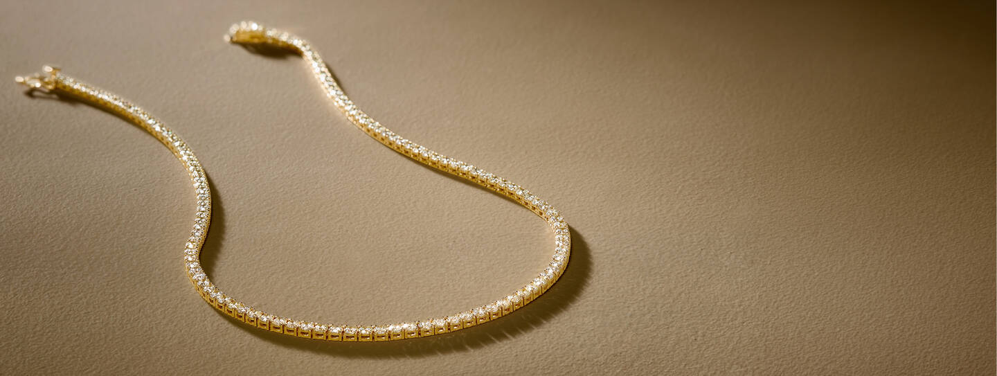 A yellow gold bracelet features round diamonds in bezel settings. 