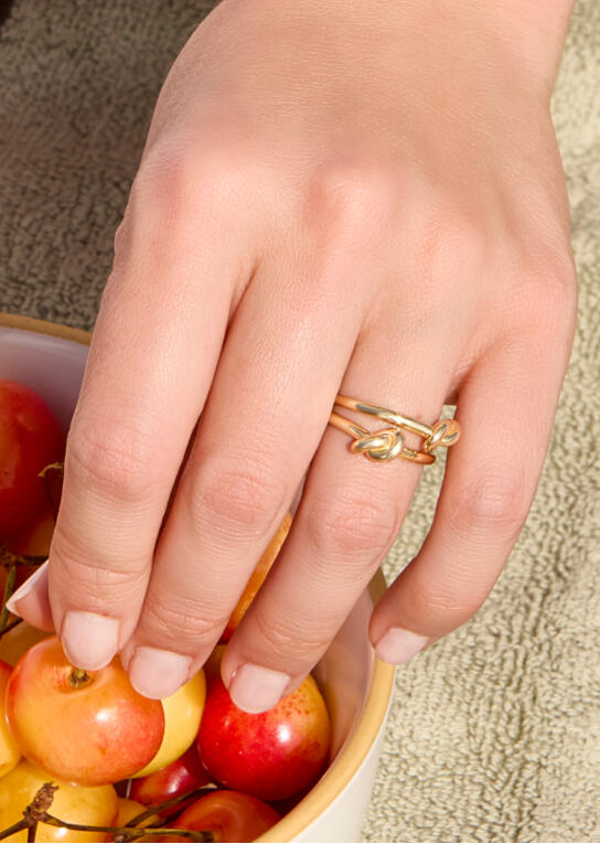A hand reaches into a bowl of cherries