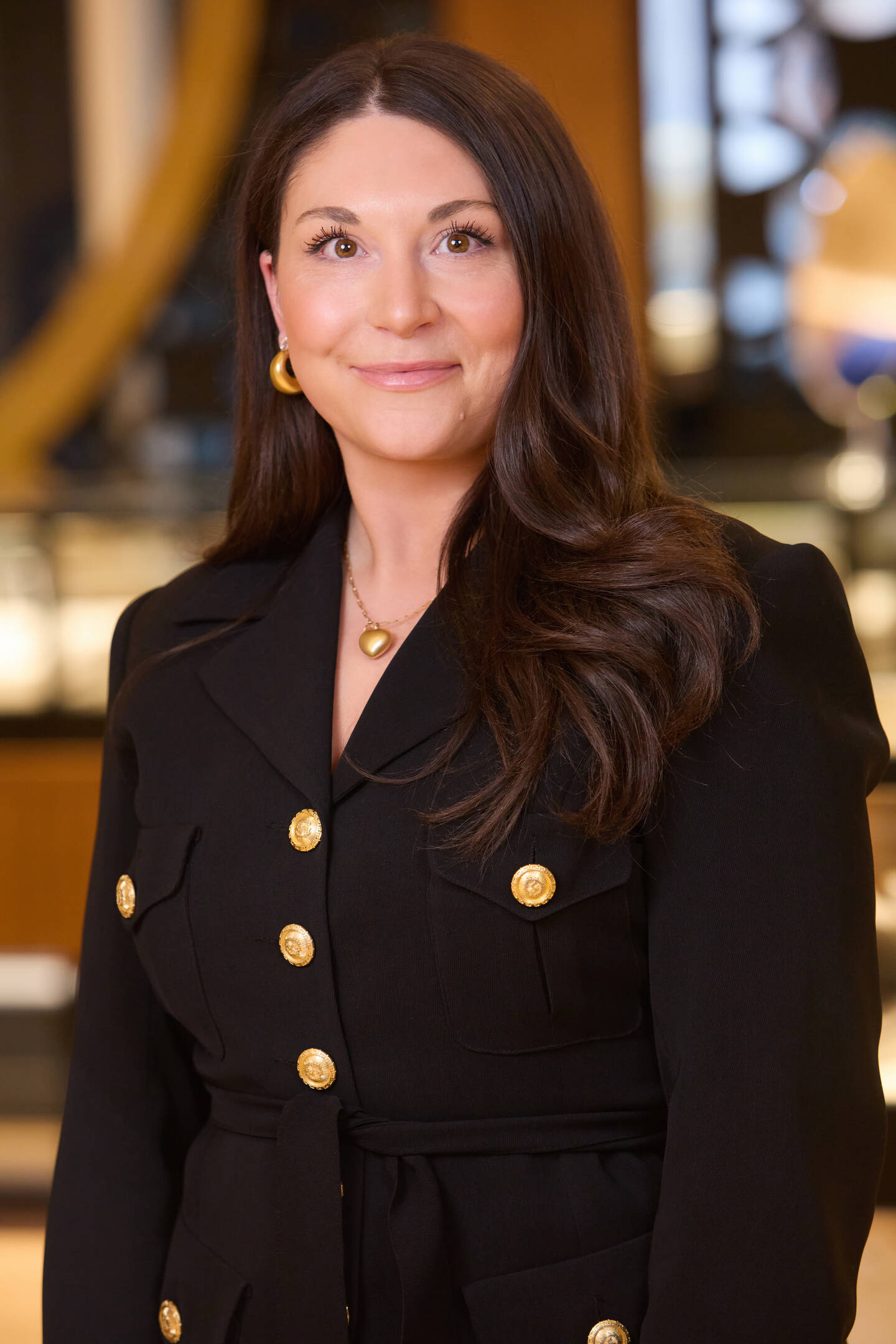 Molly Peterson wearing gold hoop earrings and a gold pendant necklace