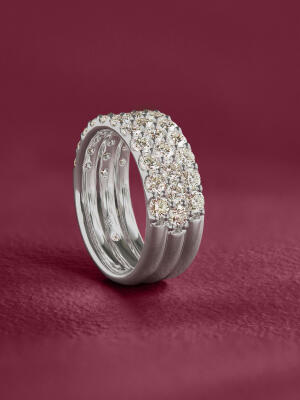 A three-row diamond band set in white gold against a purple background.