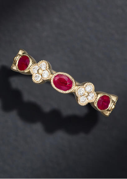 A ruby and diamond ring in 14k yellow gold on a charcoal colored background.