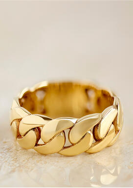 A cuban ling ring crafted in 14k yellow gold shines on a smooth surface