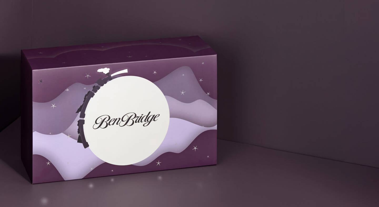 Exterior of the Ben Bridge Advent Calendar shows a train circling a moon amid clouds and stars