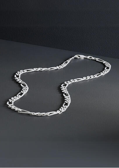 A white gold necklace rests on a gray surface.