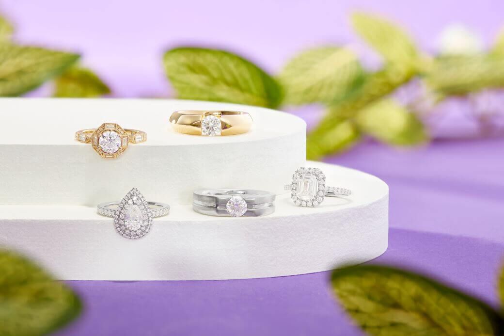 Beautiful engagement rings in various shapes and styles on a white platform with purple background 