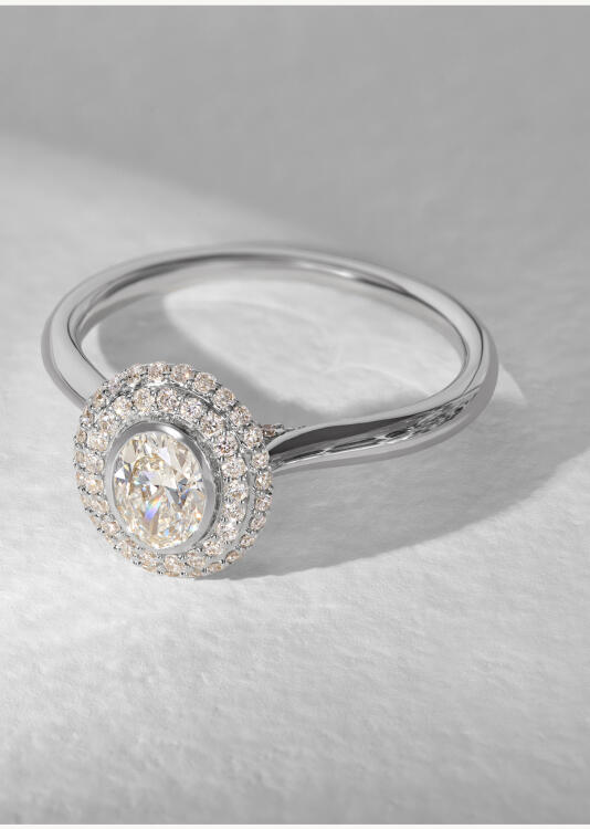 A diamond engagement ring featuring a round diamond center stone and double halo of round diamonds, all set in white gold.