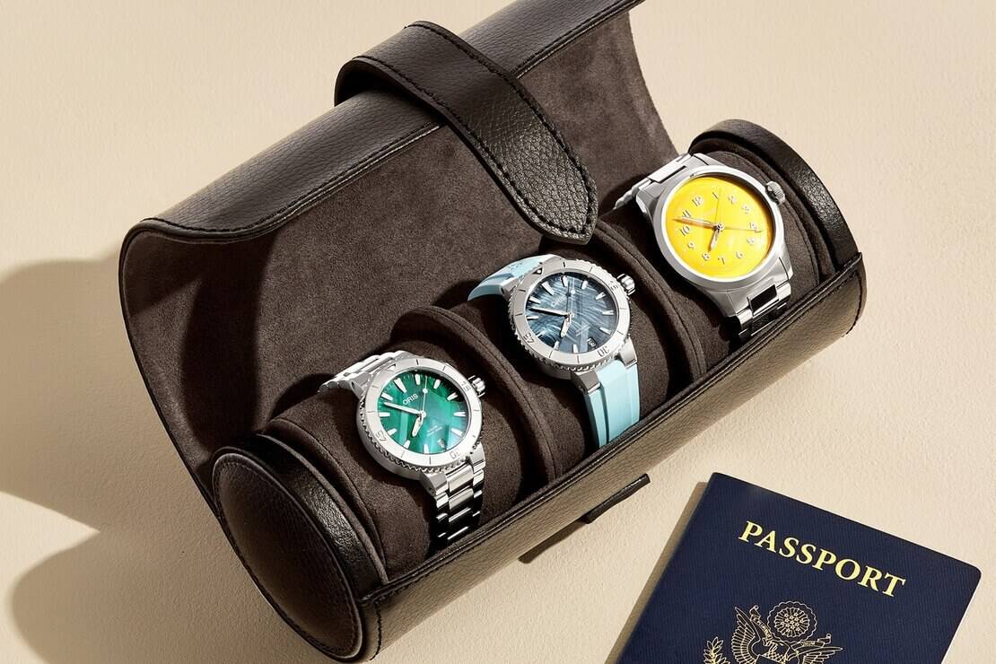 Three Oris watches in travel case with passport laying beside it
