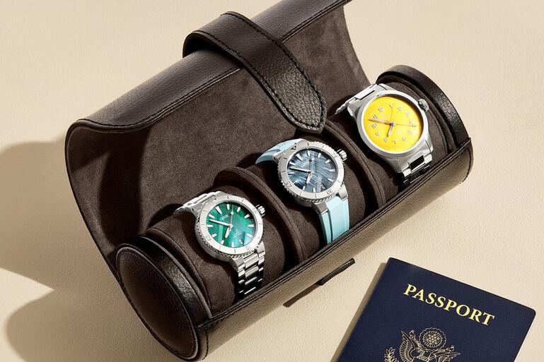 Three Oris watches in travel case with passport laying beside it