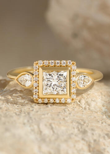 Yellow gold diamond engagement ring with a square center diamond, round diamond border and pear shaped accent diamonds.