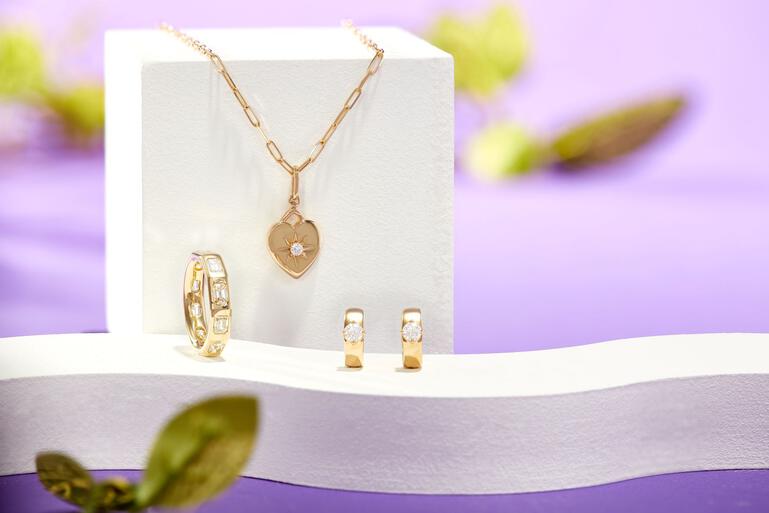 Fancy shaped diamond rings, bracelets and earrings rest on a purple and white surface