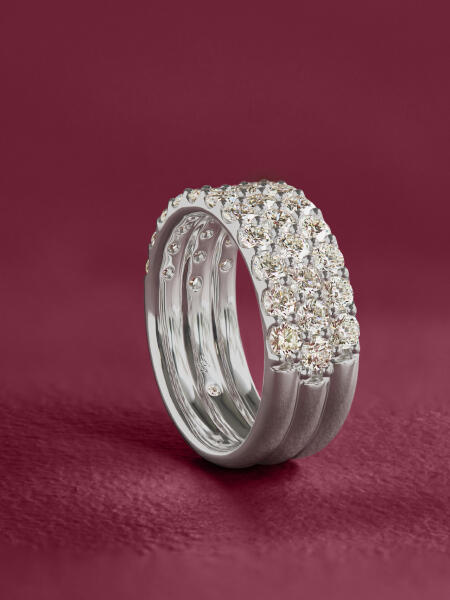 A 3-row diamond ring in white gold sparkles against a purple background.