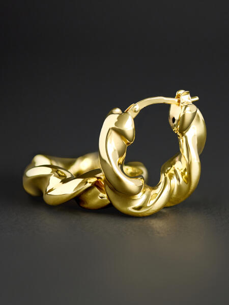 A pair of twisted gold hoop earrings on a grey background.