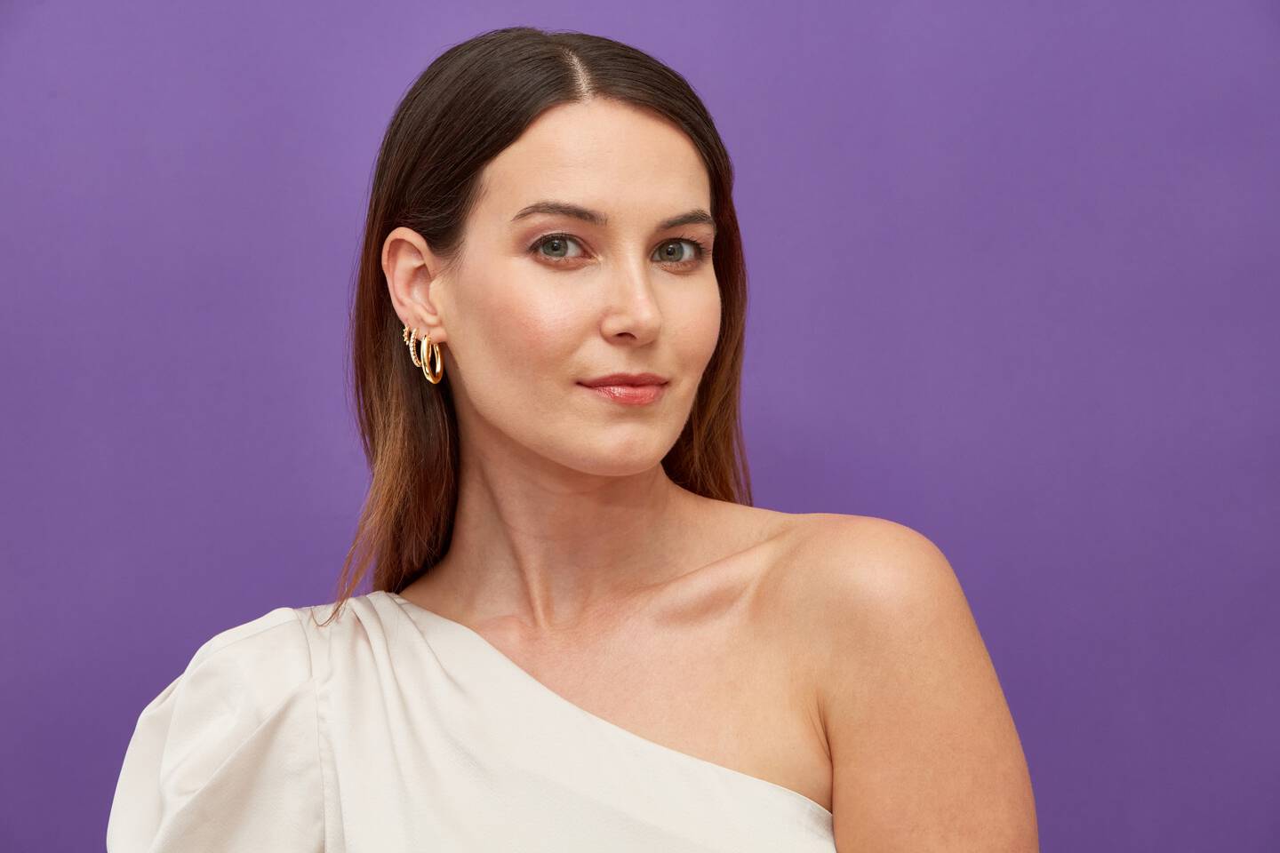 A yellow gold paperclip chain is draped across a woman's fingers
