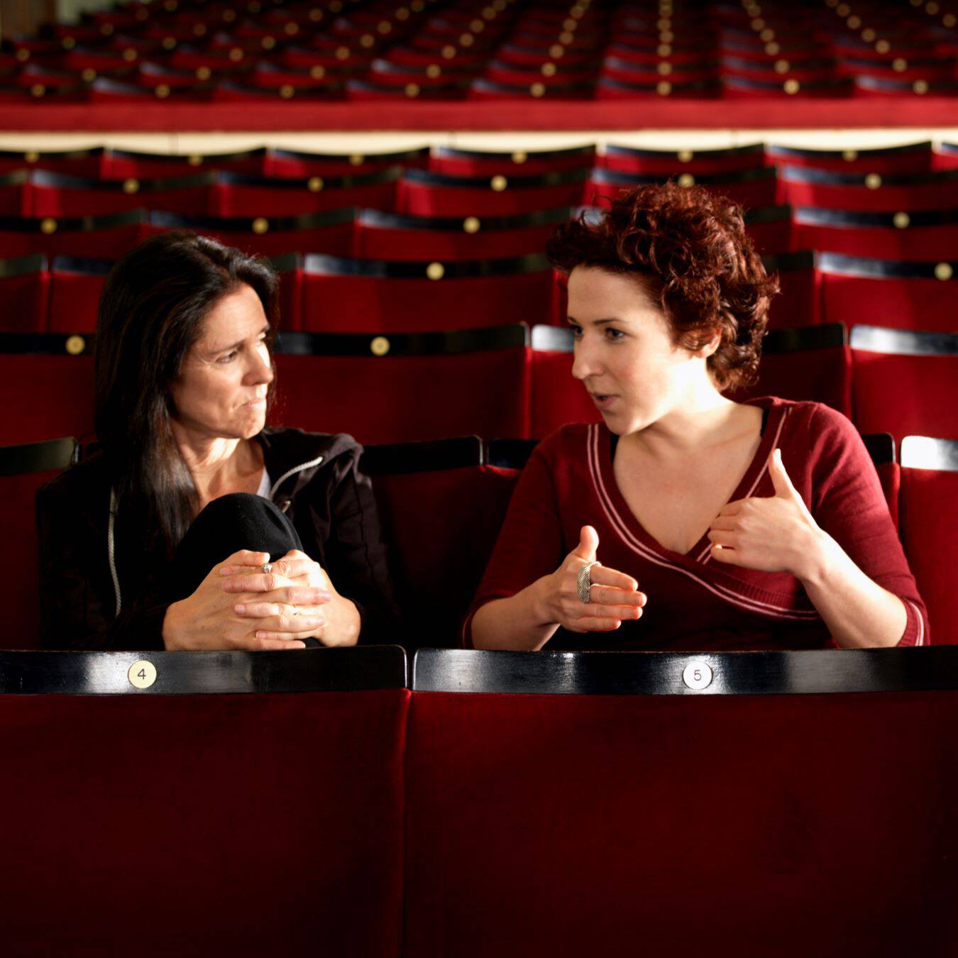 Artist and mentor sitting in a theater engaged in conversation