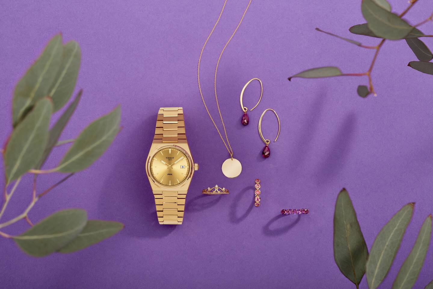 colorful gemstone jewelry and a beautiful luxury watch in gold shine against a purple background