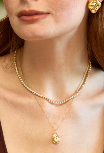 A woman in yellow gold earrings and two diamonds necklaces set in 14k yelow gold.