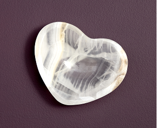 A heart-shaped onyx tray is shown from above on a textured purple surface