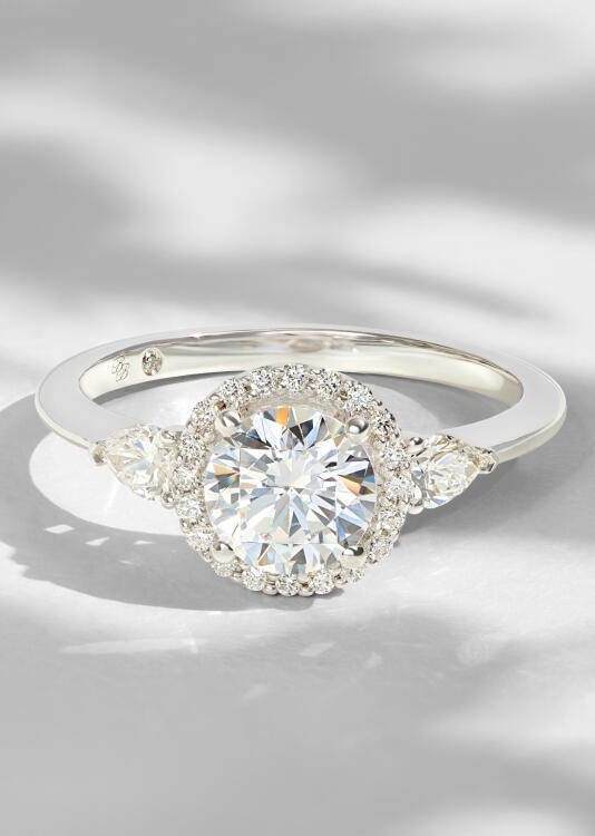 A natural round diamond engagement ring in white gold sparkles amid a halo of round diamonds.