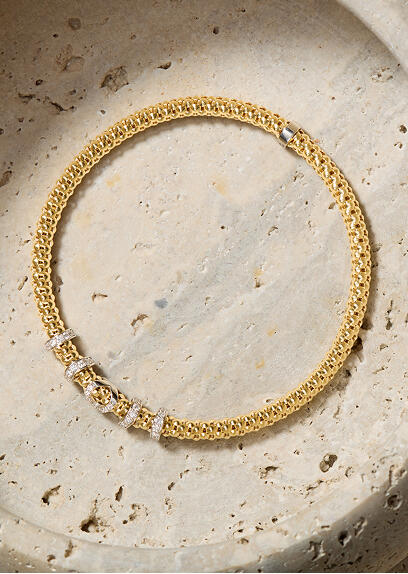 A yellow gold popcorn link bracelet with diamond stations set in white gold shines on a stone surface.