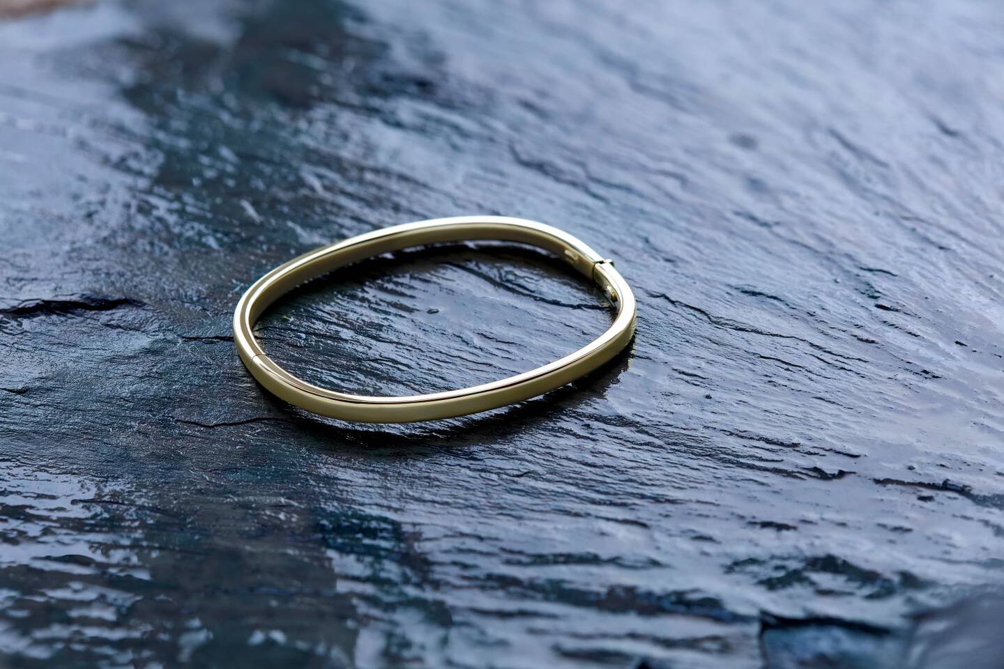 A yellow gold paperclip chain is draped across a woman's fingers