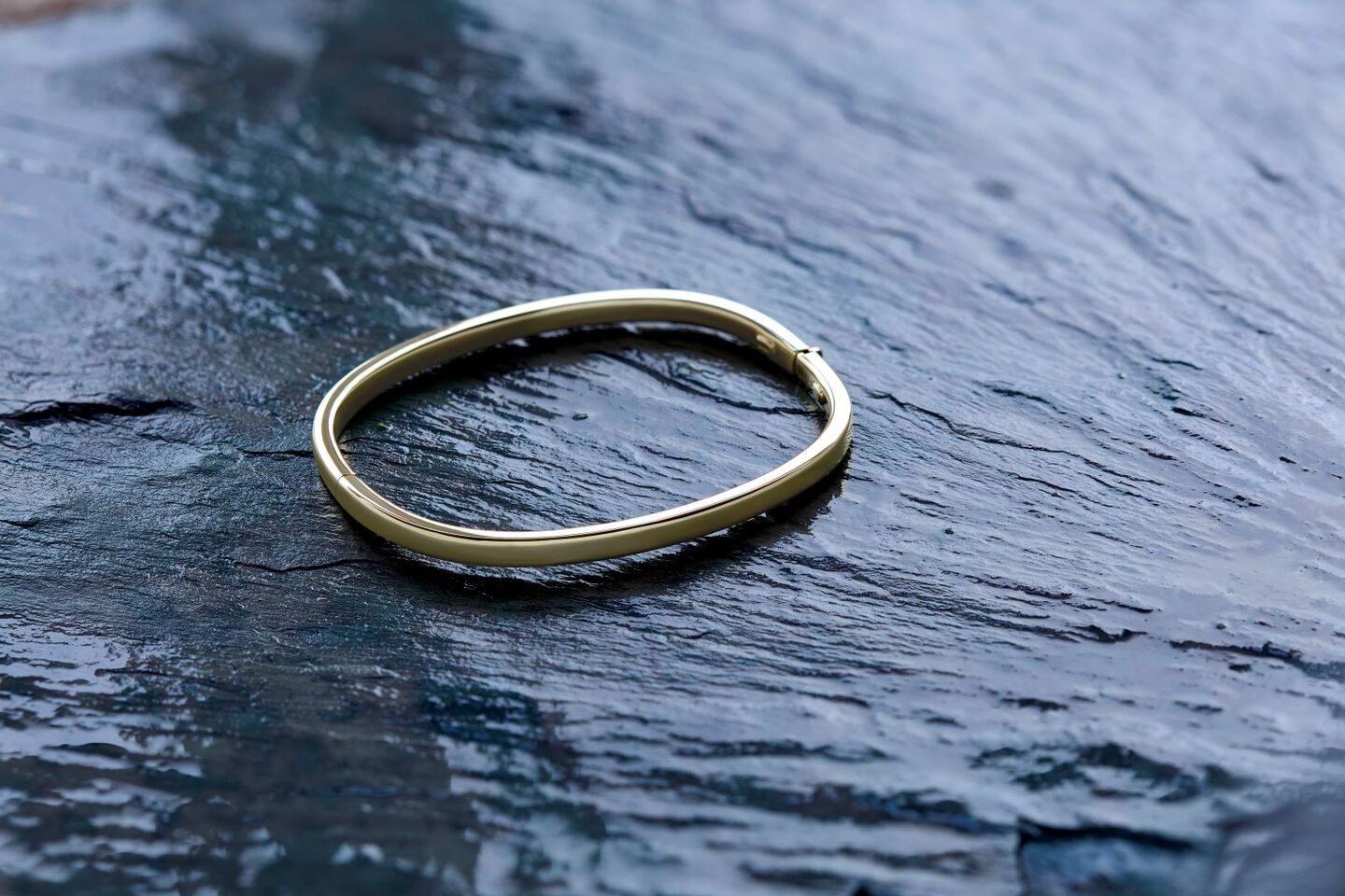 A yellow gold paperclip chain is draped across a woman's fingers