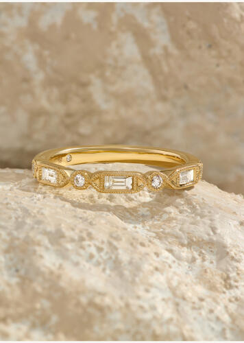 A diamond anniversary band with round and baguette diamonds set in 14k yellow gold.
