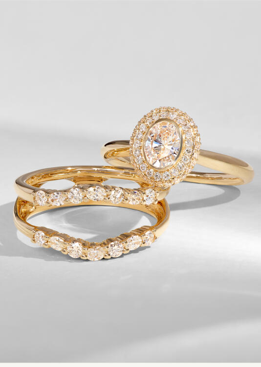 A wedding set featuring a halo diamond engagement ring and wedding band with a double shank and round diamonds, all set in yellow gold.