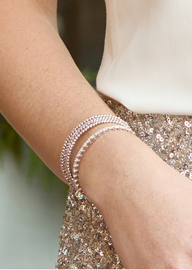 A woman&rsquo;s wrist resting by the waist. She is wearing two bracelets that sparkle.