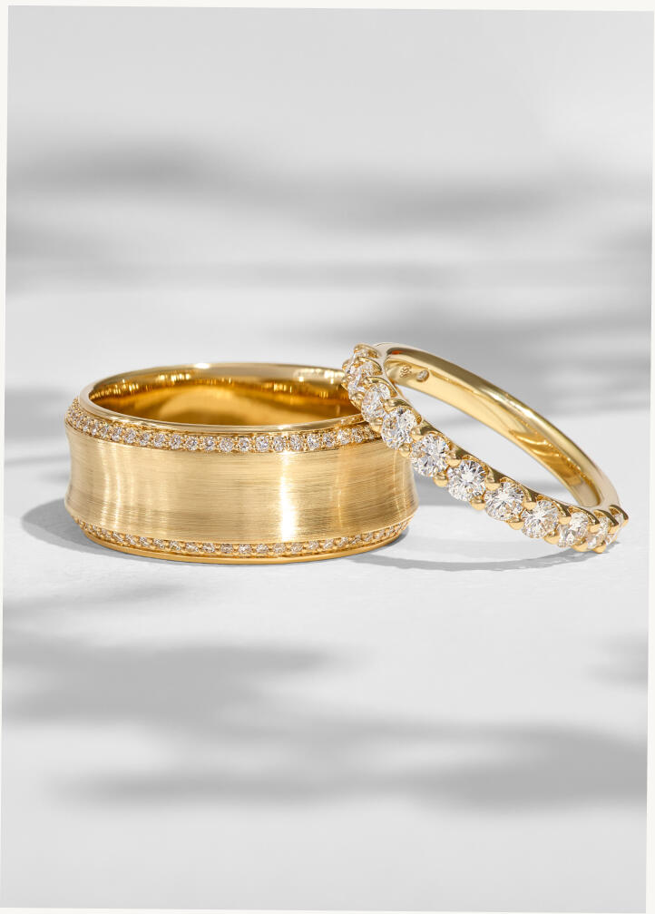 A diamond anniversary band leans against another band of yellow gold