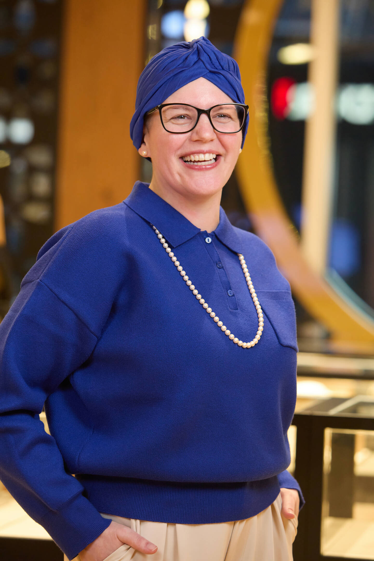 Kendra Lindell smiling. She is wearing a blue shirt with pearls and a blue hat. 