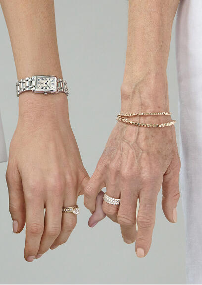 Hands of mother and daughter entwined, both wearing luxury jewelry.