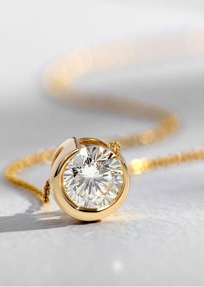 A round diamond in a half moon bezel setting of 14k yellow gold is strung on a yellow gold necklace.