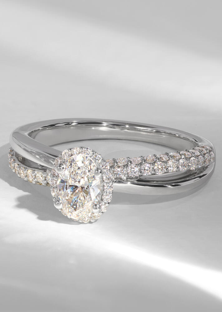 An oval diamond halo ring in white gold with a twisted shank