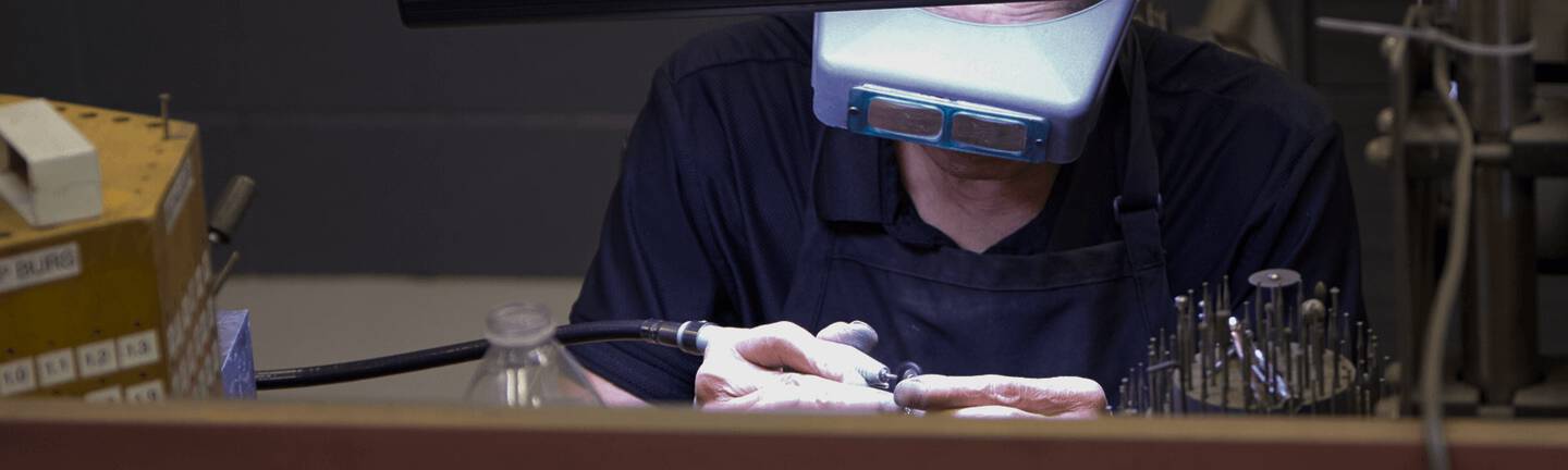 Jewelry repair expert is working on fine jewelry with a pair of magnifying goggles.